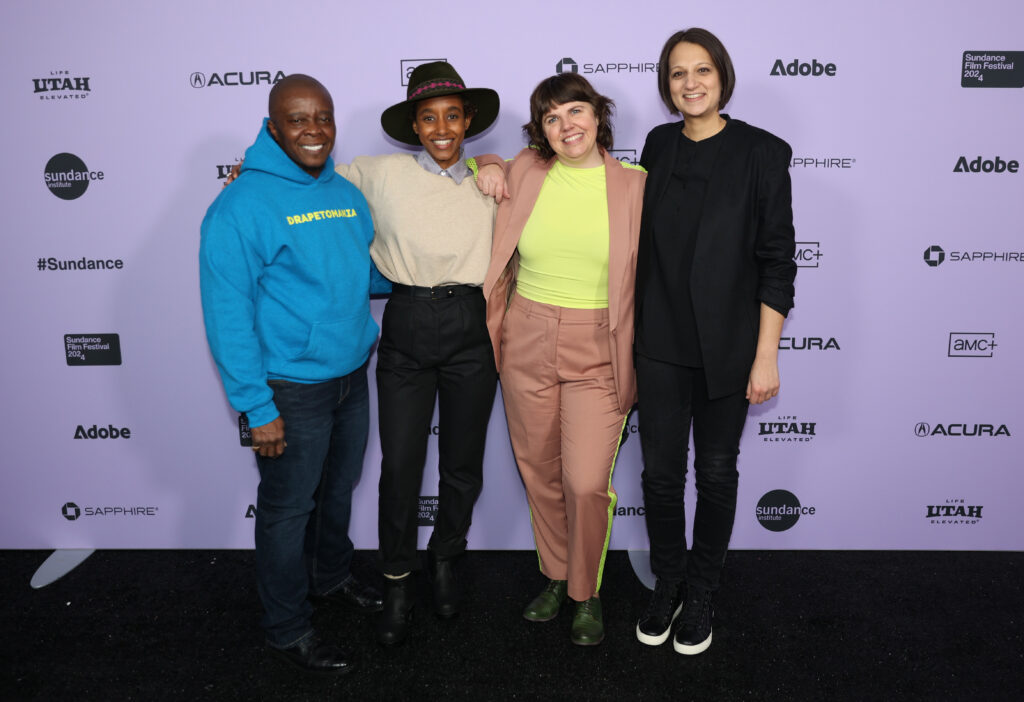 Yance Ford, Netsanet Negussie, Jess Devaney, and Sweta Vohra pose together in front of a white 2024 Sundance Film Festival backdrop.