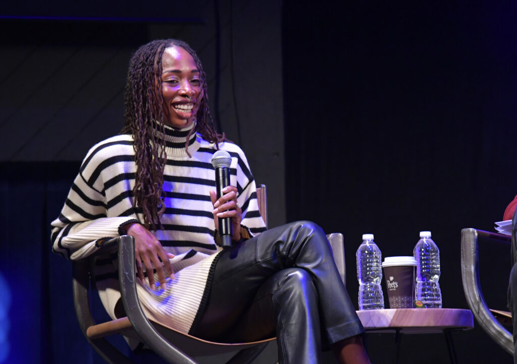 Mariama Diallo sits on stage at the Egyptian Theatre holding a microphone and smiling.
